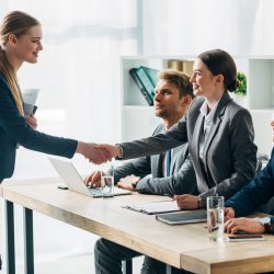 Smiling employee shaking hands with recruiter in office